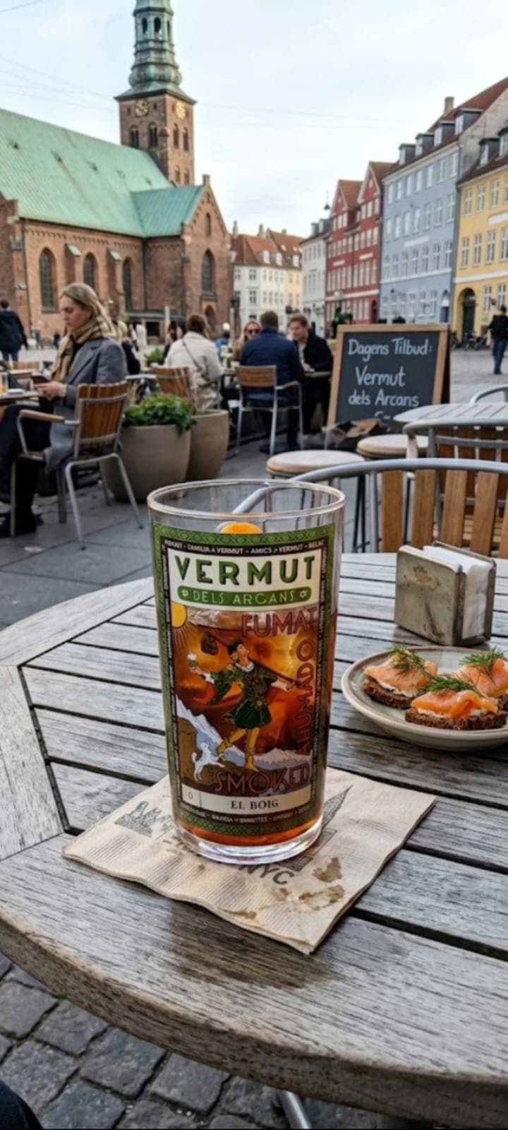Got de Vermut dels Arcans El Boig en una terrassa de Copenhaguen amb la catedral i cases de colors de fons
