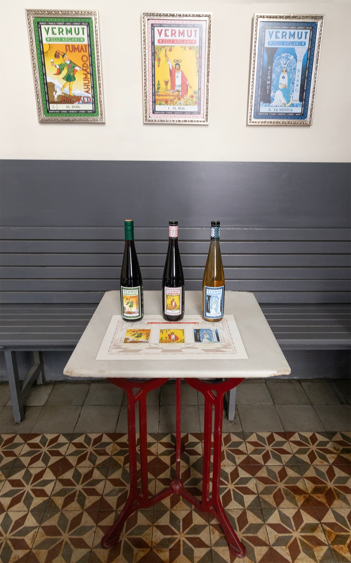 Les tres ampolles de Vermut dels Arcans sobre una taula bistrot al Bar Calders