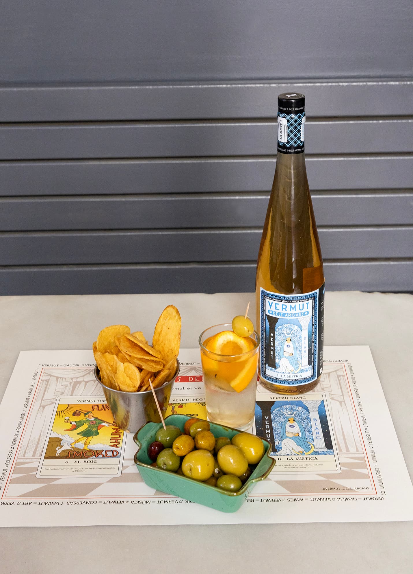 La Mística servida amb patates, olives i copa sobre el mantell
