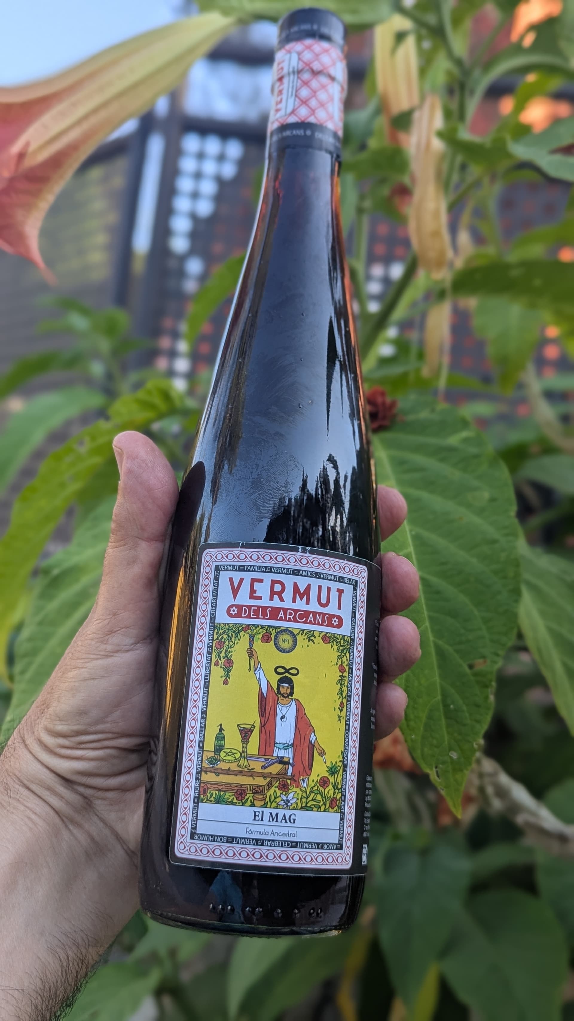 Ma sostenint ampolla El Mag de Vermut dels Arcans entre vegetació