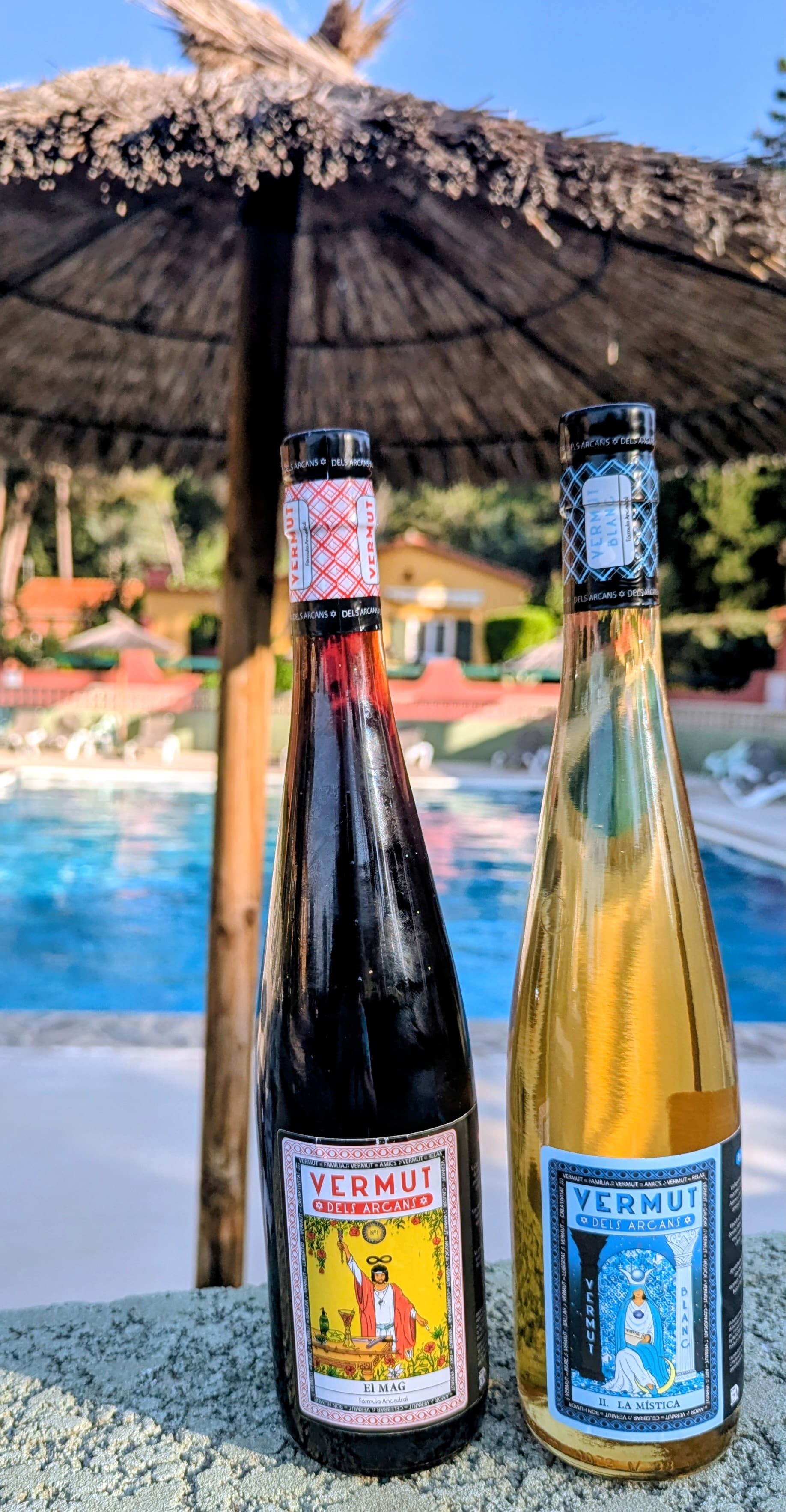 El Mag i La Mística davant piscina amb para-sol de palla a l'estiu
