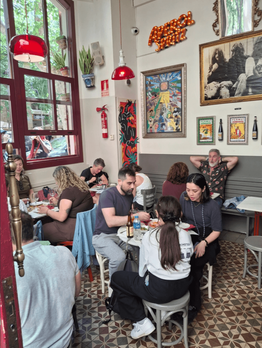 Interior del Bar Calders ple de gent menjant i bevent amb els quadres dels Arcans a la paret