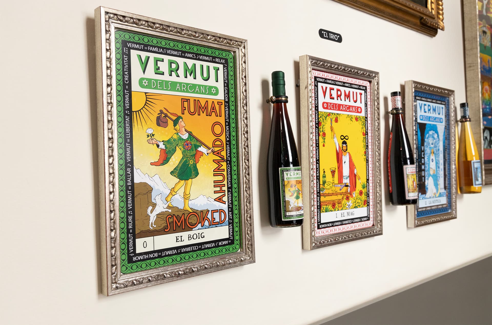 Els tres quadres emmarcats de Vermut dels Arcans a la paret, vistos de costat